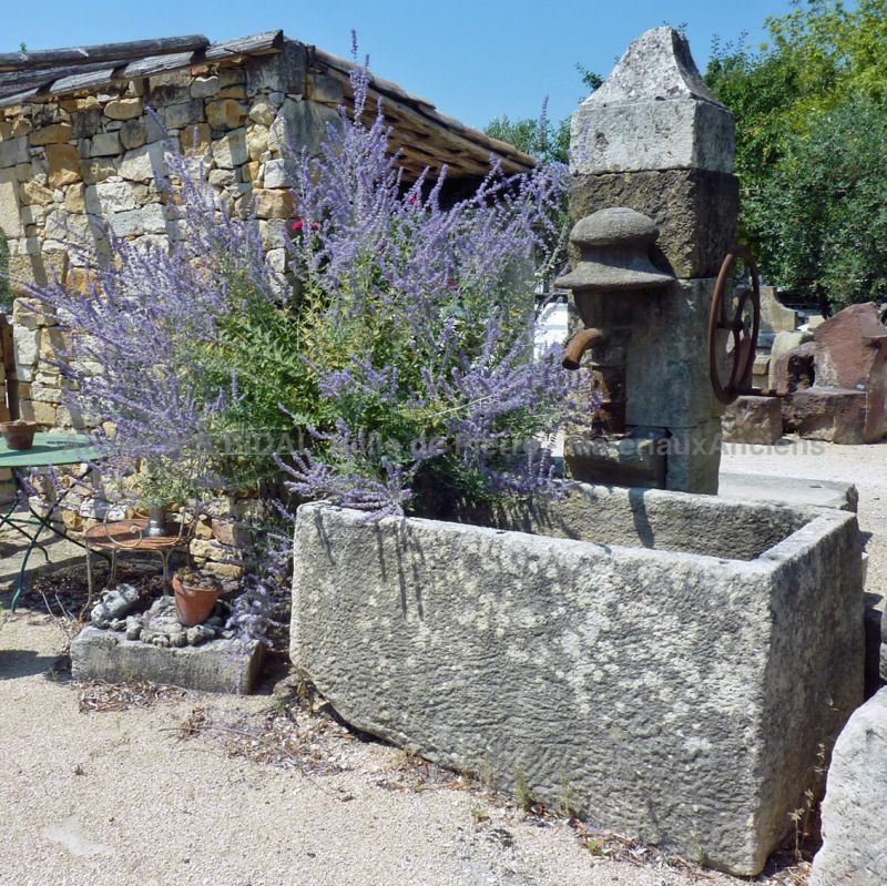 Stone wall fountain sold with its vintage hand pump made of cast iron.