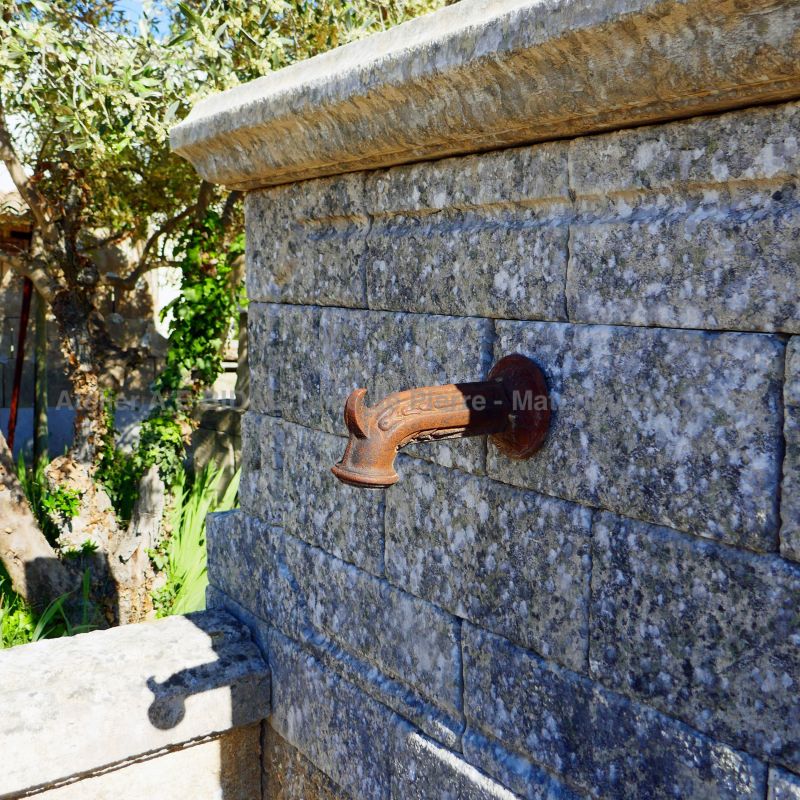 Wall fountain in old stones : detail of the pediment and the water outlet