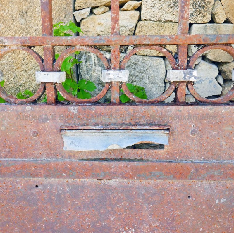 Portail ancien : un portail ancien en fer forgé décoré de volutes et dôté d'une boite aux lettres