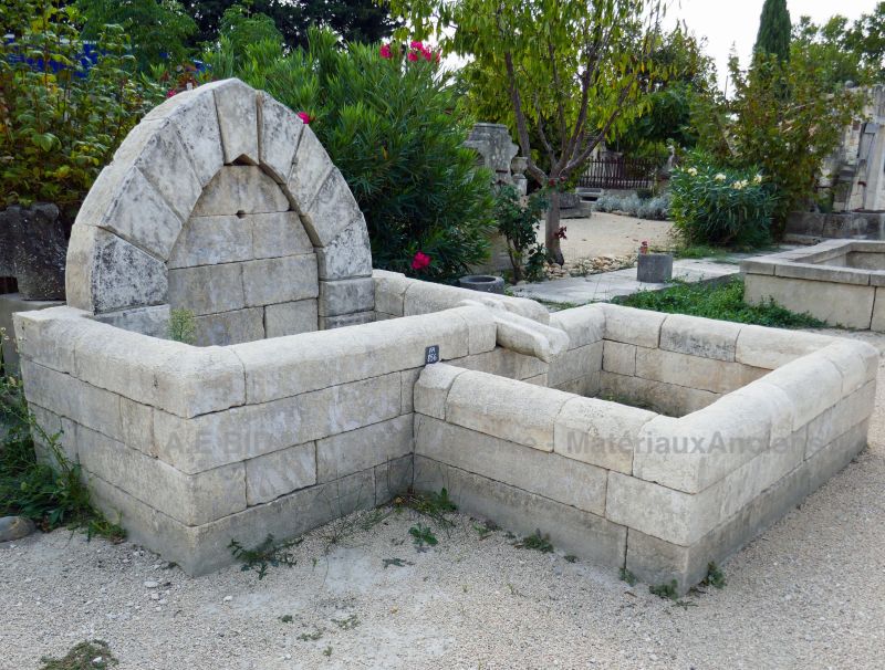 Fontaine de jardin en pierre ancienne avec deux bassins et un fronton.