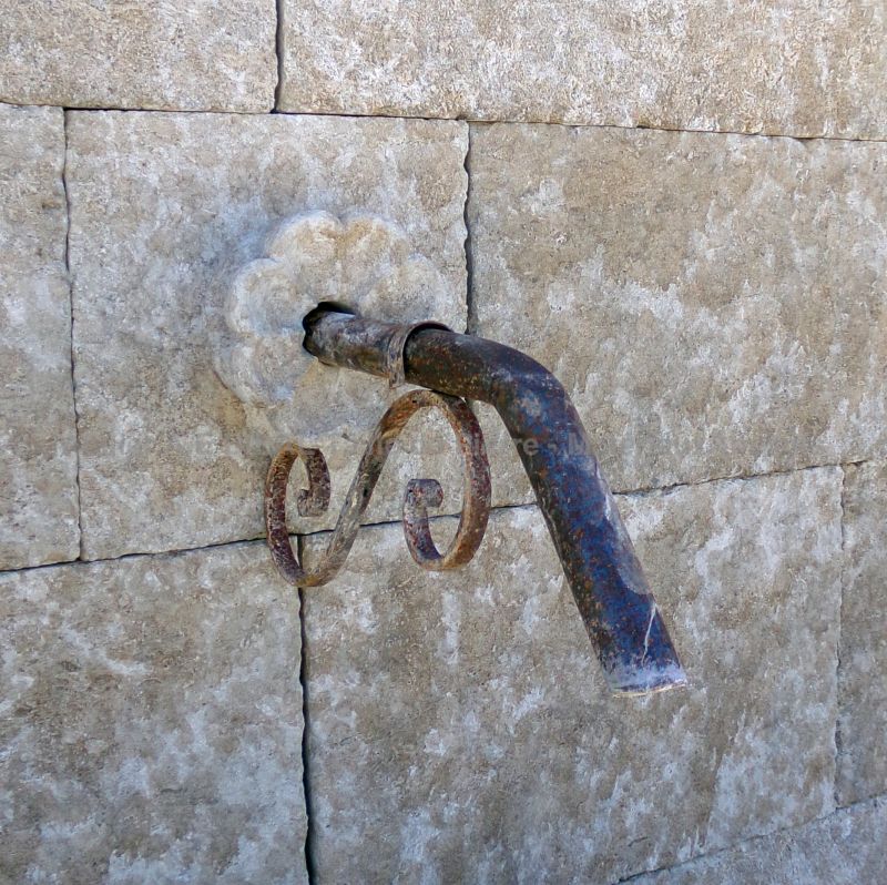 Sortie d'eau en fer forgé et rosace sculptée en pierre sur notre fontaine murale : Atelier Alain BIDAL, Provence