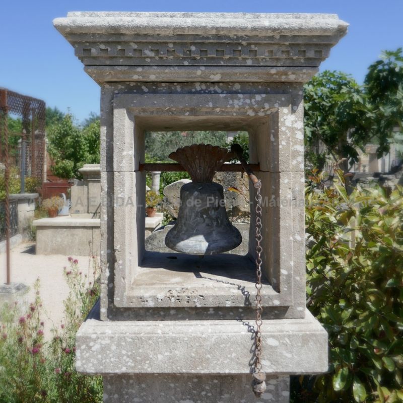 Antique bell for an entrance door and its ancient stone pillar.