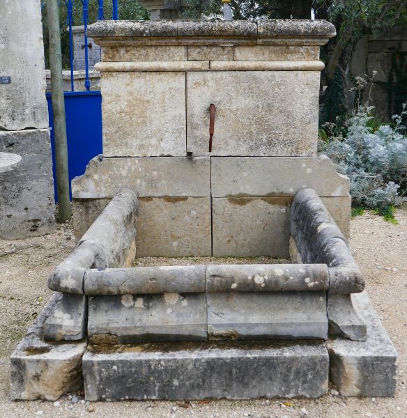 Fontaine ancienne - une fontaine murale en pierre avec détail en fer forgé.