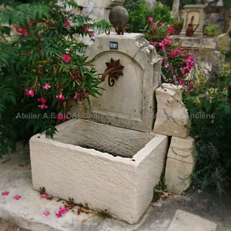 Wall fountain with cast iron water outlet and stone trough.