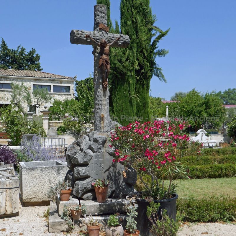 Monument made of old materials: stone cross and Christ made of wrought iron.