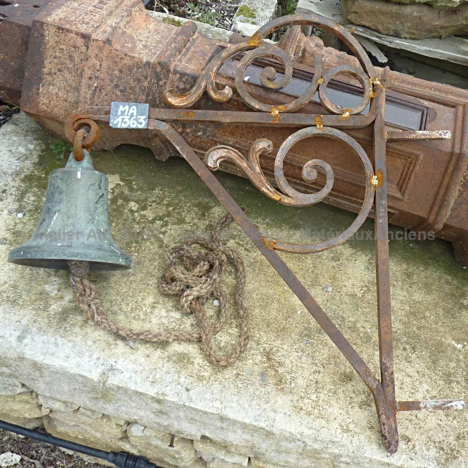 Wonderful antique bronze wall-mounted bell with its wrought iron hanging arm