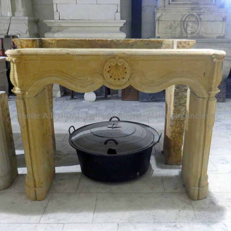 Cheminée ancienne Louis XV en pierre naturelle dorée à vendre parmi un large choix chez Alain BIDAL