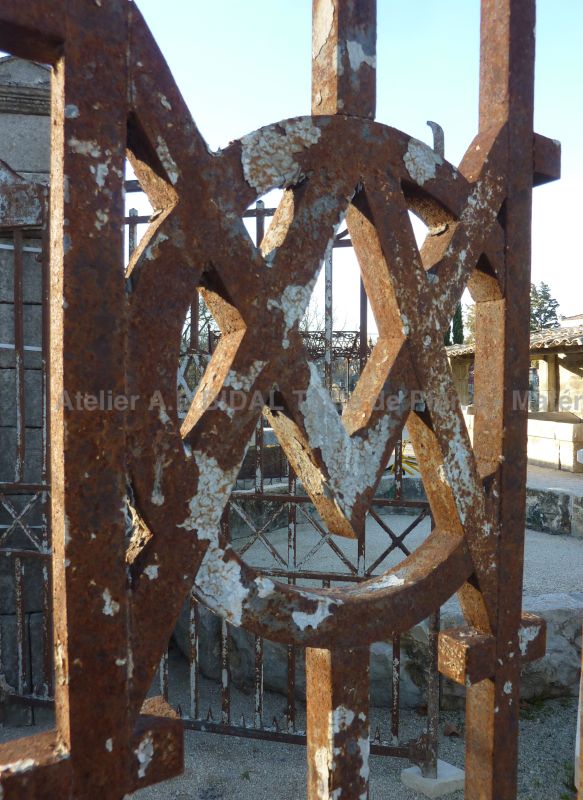 Initiales entrelacées sur portail ancien en fer forgé.