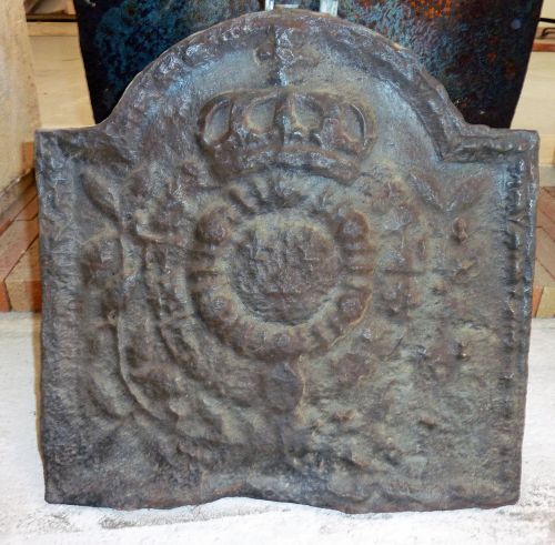 Une plaque décorative cheminée en fonte ancienne représentant les armoiries royales.
