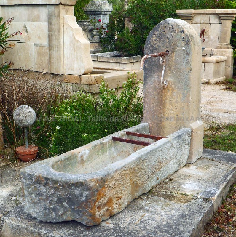 Fontaine murale d'aspect rustique : fontaine d'extérieur avec ancienne auge et borne massive