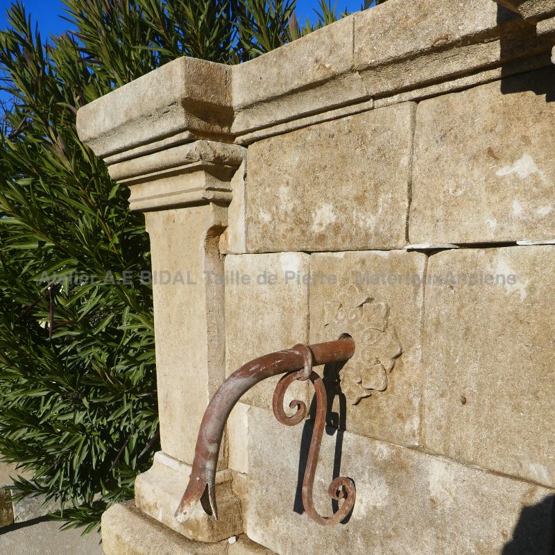 Sortie d'eau en fer forgé et rosace sculptée en pierre sur notre fontaine murale : Atelier Alain BIDAL