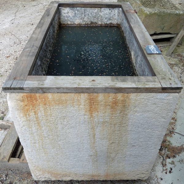 Bac rectangulaire en matériaux anciens: un bac en pierre et bois.