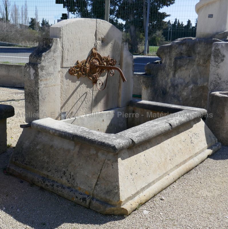 Antique stone fountain with cast-iron rosette and basin with splayed edges