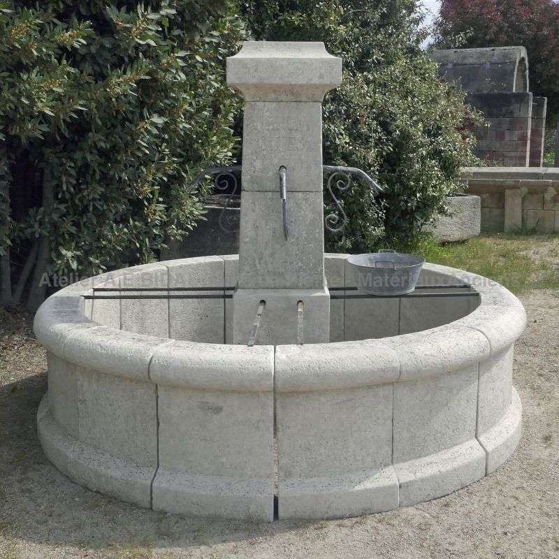 Rustic-looking fountain in weathered stones : round basin and square column - Atelier Alain BIDAL (France)