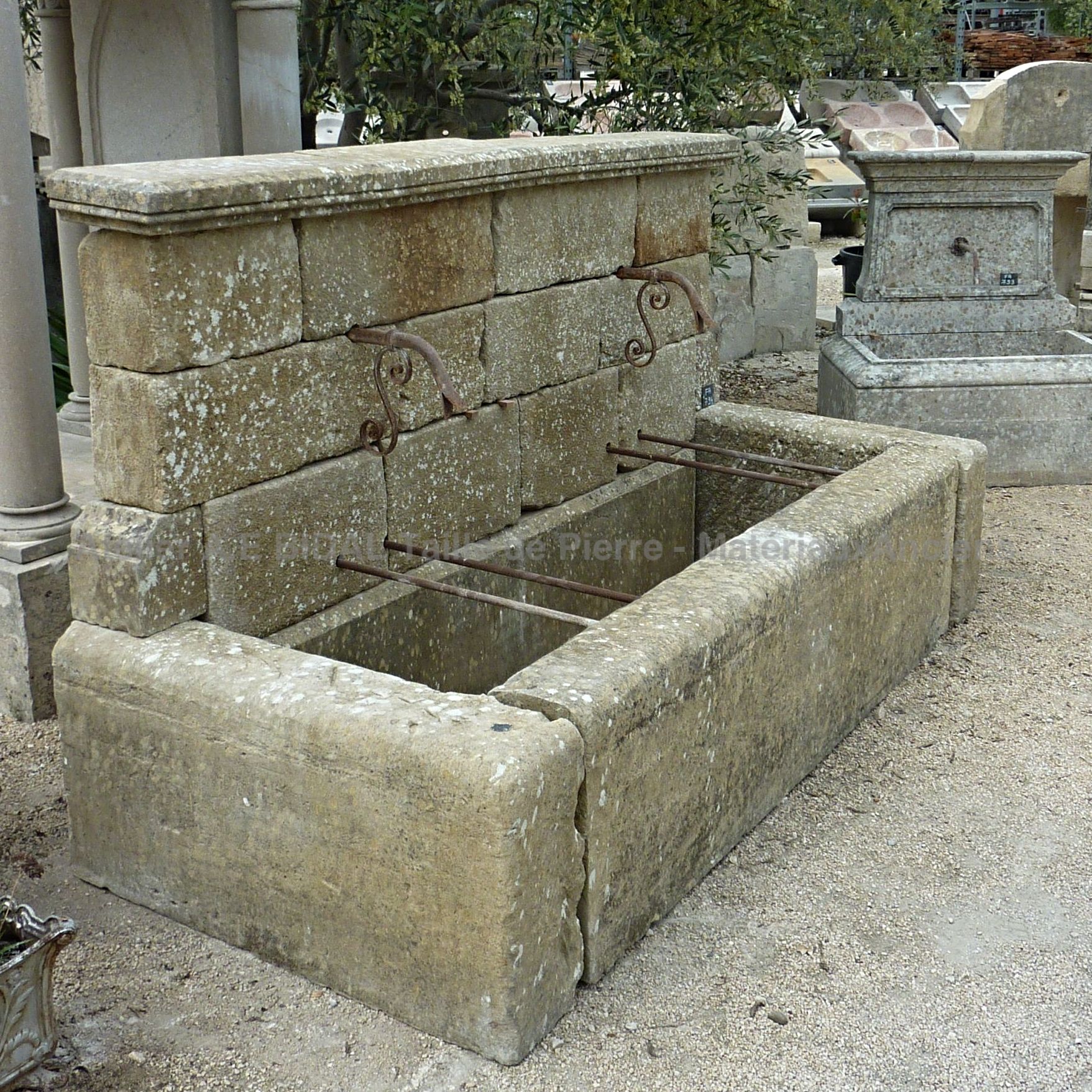 Fontaine murale en matériaux anciens: pierre ancienne, fer forgé et métal.