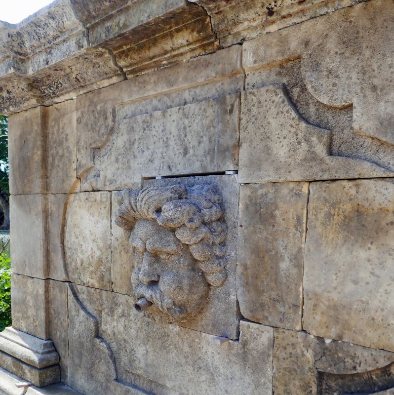 Détail de la tête d'Éole sculptée à la main en guise de sortie d'eau sur le fronton de notre grande fontaine en pierre