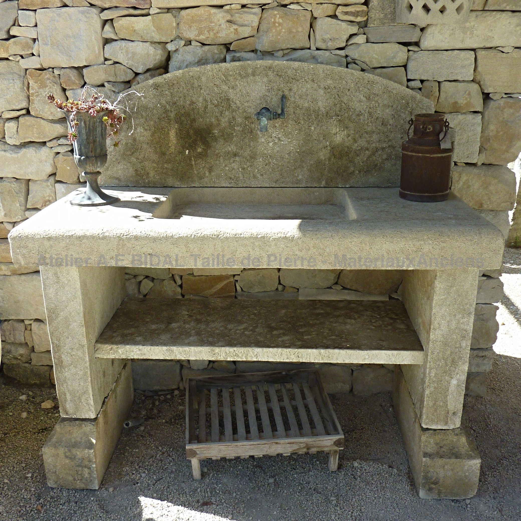 Bel evier en pierre ancienne sur jambages pour une cuisine résistante.