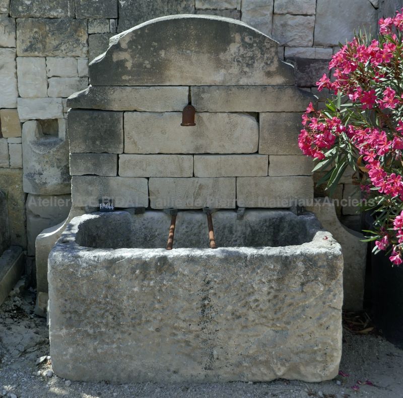 Outdoor fountain with antique stone trough and pediment in stone.