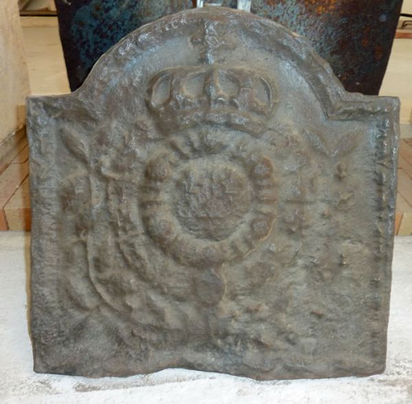 Une plaque décorative cheminée en fonte ancienne représentant les armoiries royales.