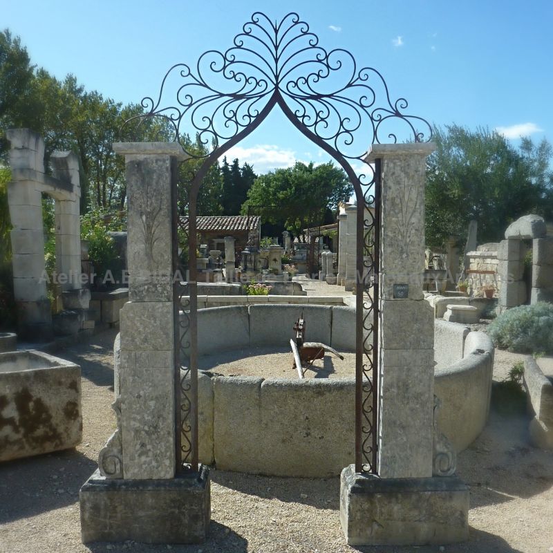 Anciens piliers en pierre naturelle - une paire de piliers de toute beauté avec son arche en fer forgé à volutes.