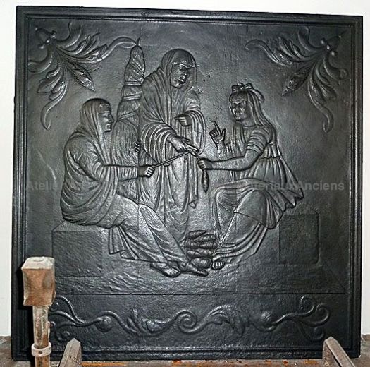 Une plaque de cheminée en fonte avec décor représentant les sœurs Parques - nos accessoires cheminée mythologie romaine.
