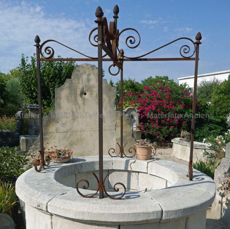 Old ironwork on the stone garden well on sale at Atelier Alain BIDAL.