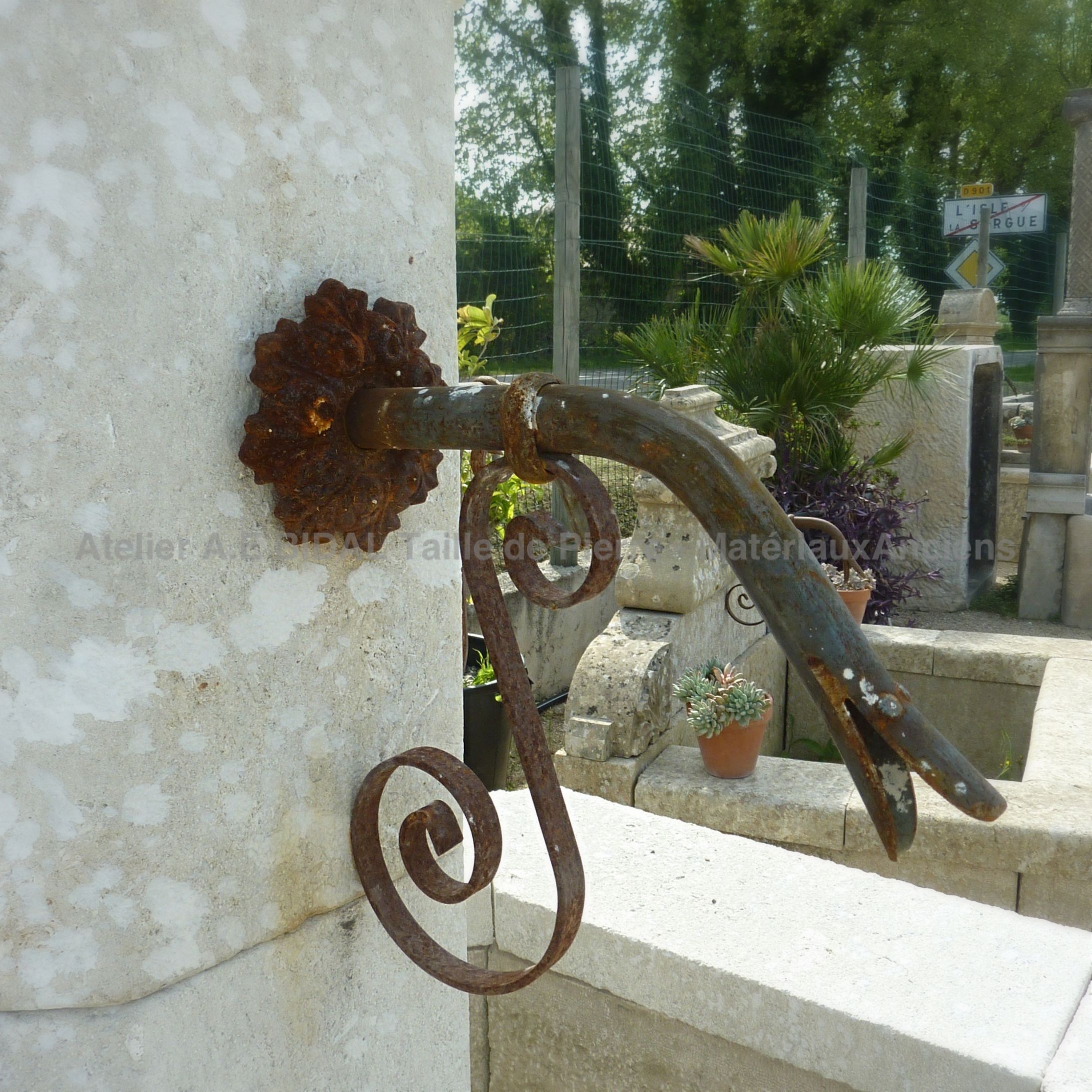 Détail de la sortie d'eau forgée de notre fontaine de Provence en pierre naturelle.