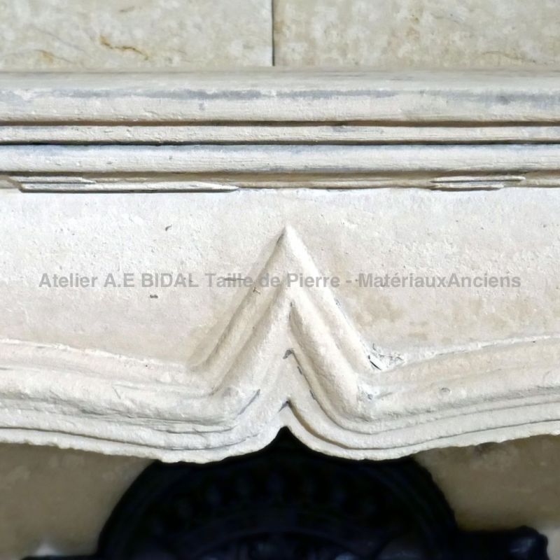 Détails des très fines moulures sculptées à la main sur notre cheminée Louis XV en pierre blanche.