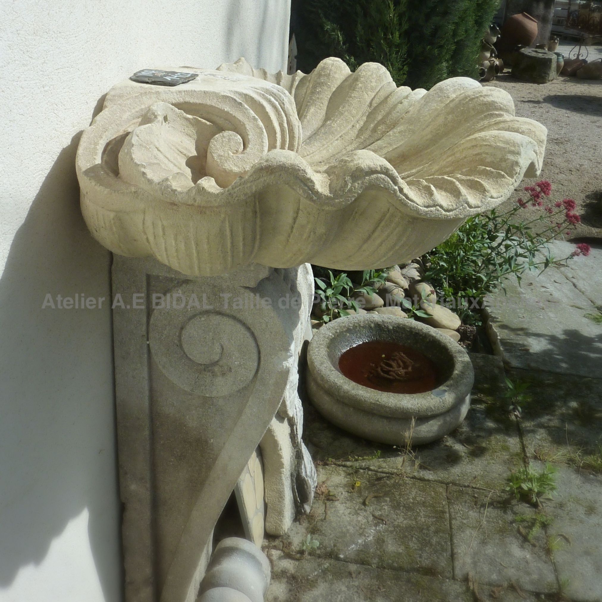 Magnifique fontaine à eau - vasque sculptée en coquille sur pied à volutes - Matériaux anciens Bidal.