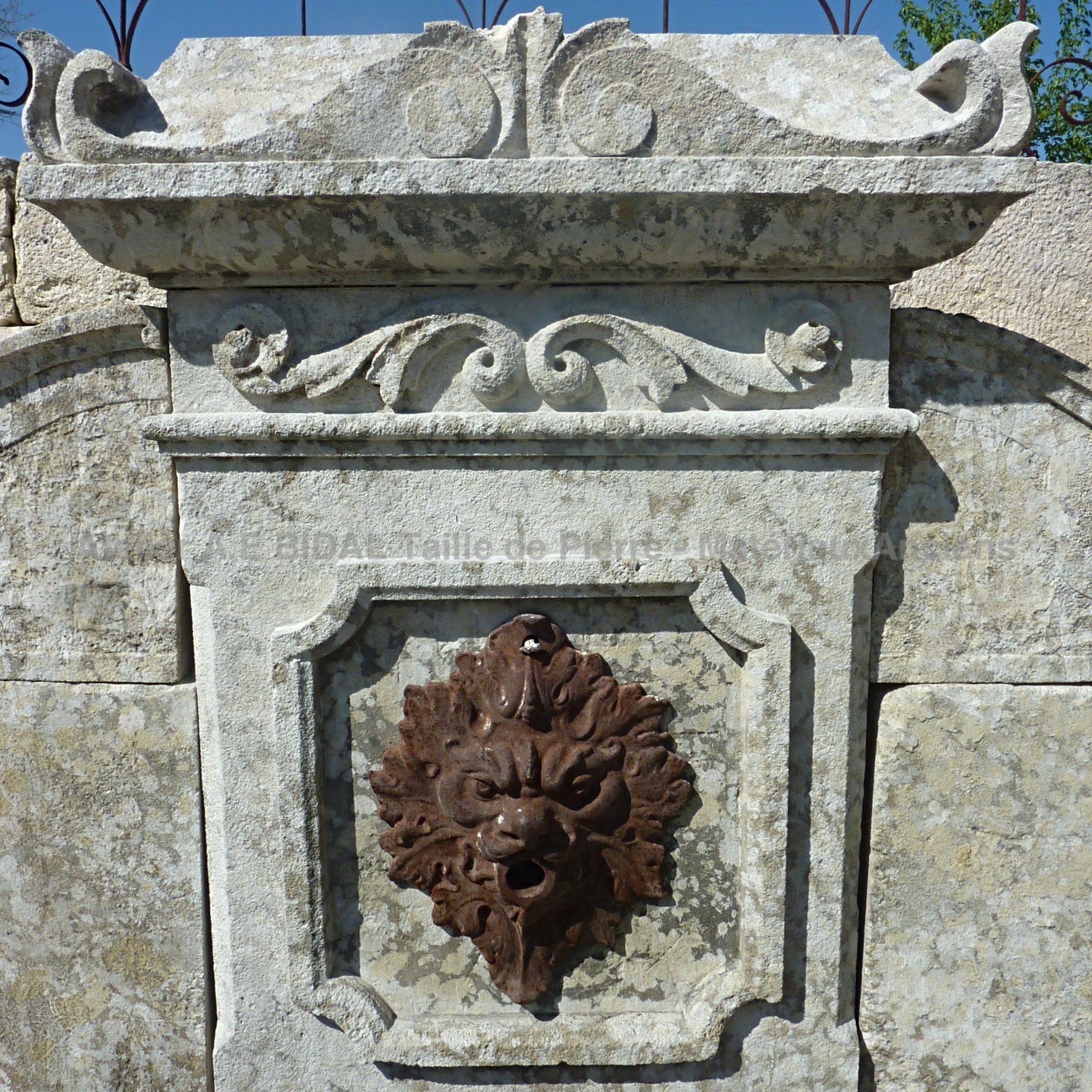 Détail de la sortie d'eau en fonte sur notre fontaine murale en pierres anciennes | Fontaine en pierre avec tête de lion en fonte.