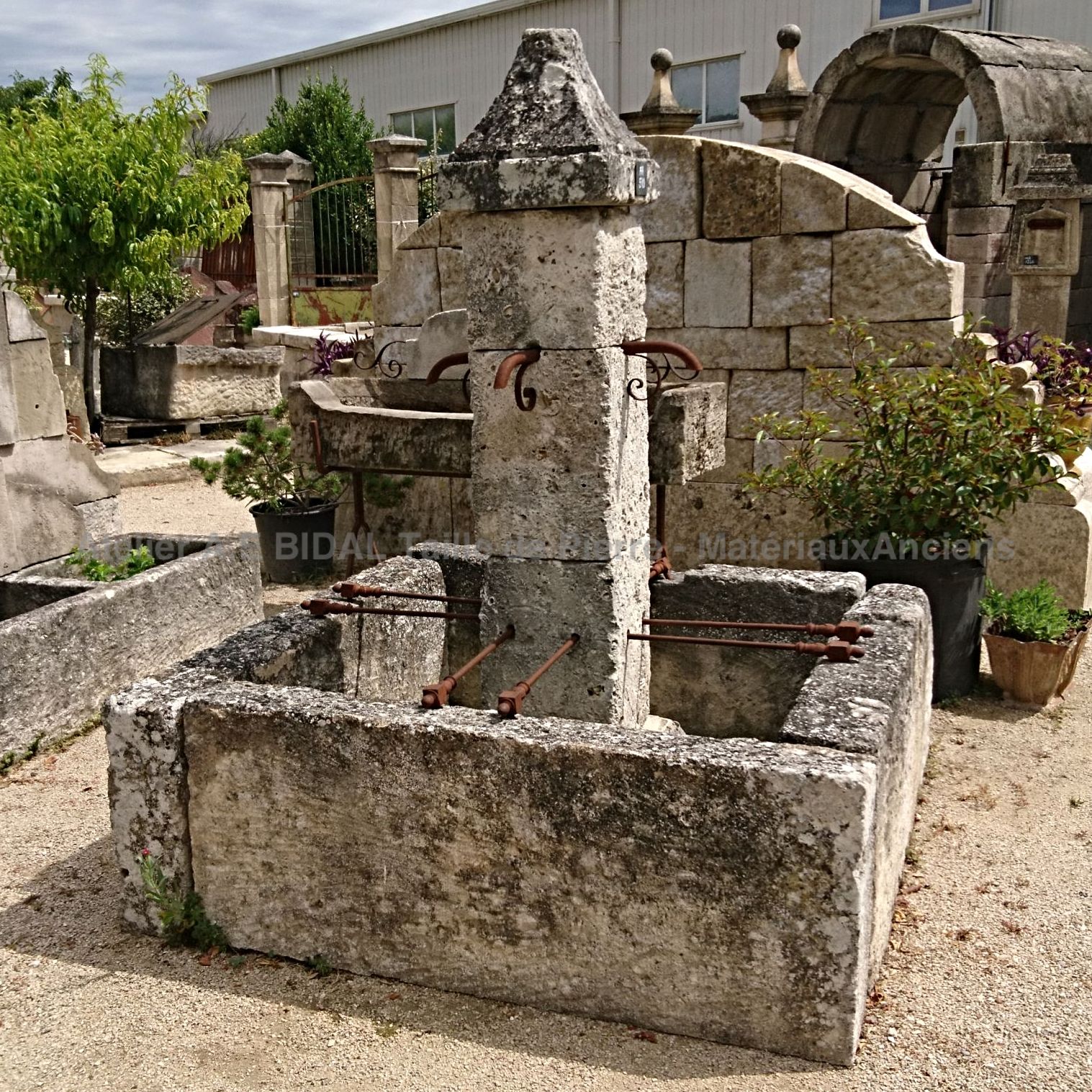 Belle fontaine centrale - une fontaine d'extérieur avec bac carré en pierre naturellement usée par le temps.