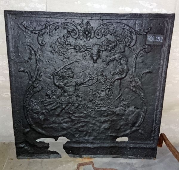 Plaque de cheminée en fonte ancienne représentant une scène d'affrontement dans la mythologie.