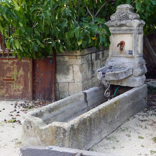 Grande fontaine murale avec bac ancien et fronton à rosace en fonte.
