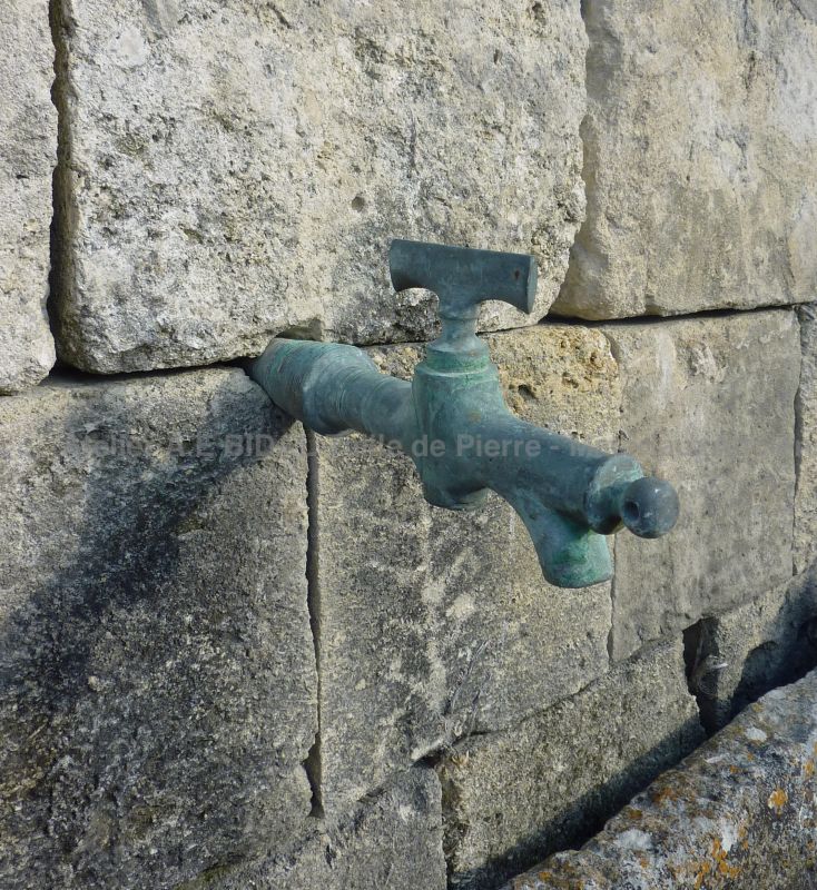 Old metal faucet on our antique wall fountain in stone.