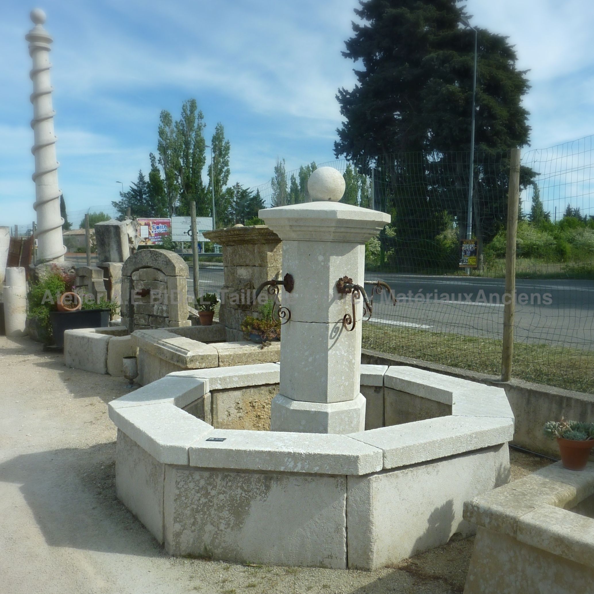Fontaine centrale avec un bassin : une fontaine de jardin faite de pierres et de fer forgé.