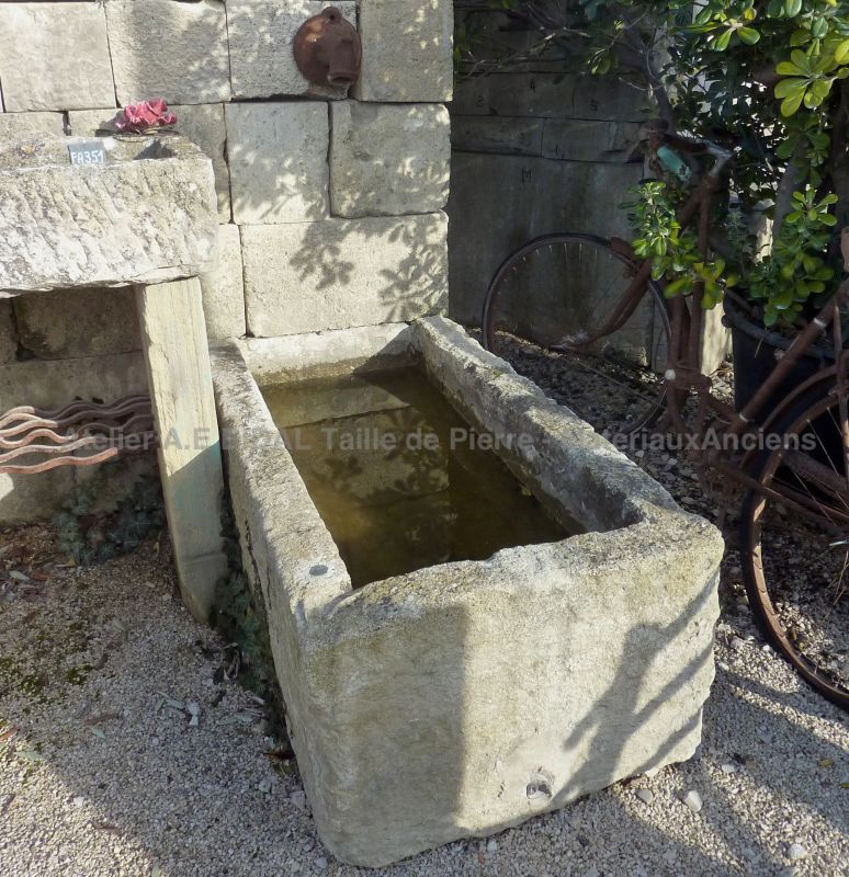 Antique monolithic stone trough on our garden wall fountain in old stones.