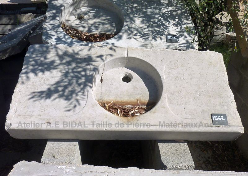 Un évier ancien en pierre - bac circulaire et égouttoirs.