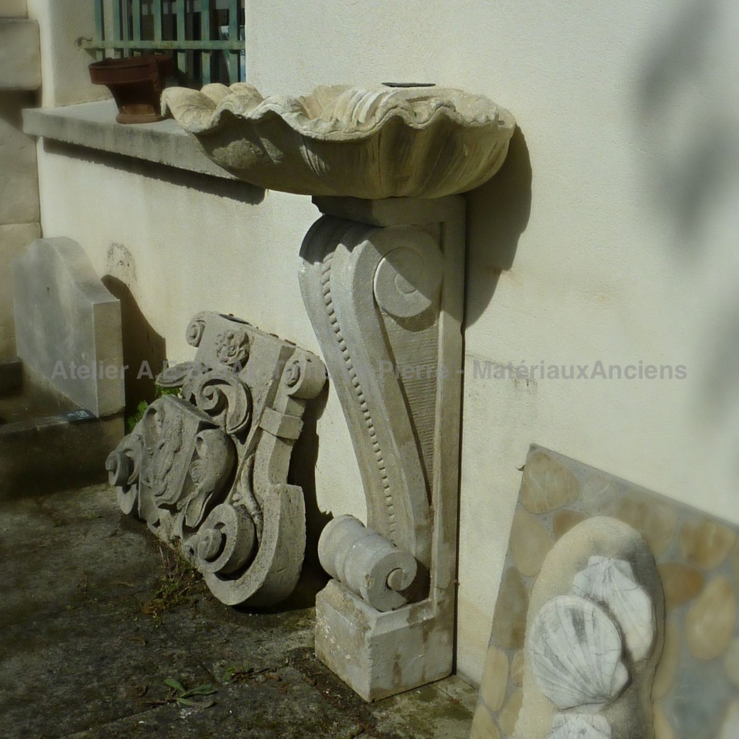 Vasque sculptée main en forme de coquille et pied mouluré : une fontaine au charme italien.