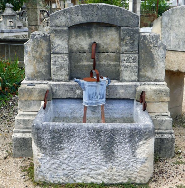 Wall fountain with pretty pediment and bucket-rest bars made of antique materials | Outdoor fountain with monolithic trough.