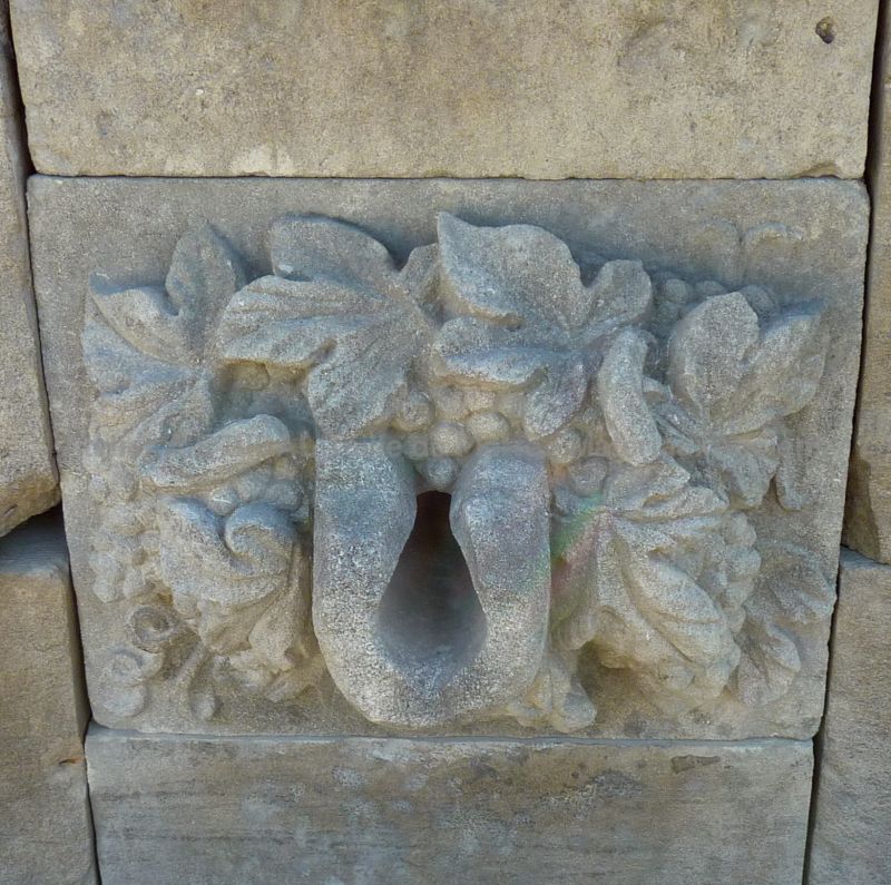 Detail of the sculptures on the pediment of our stone wall fountain : spillway decorated with grapes and foliage.