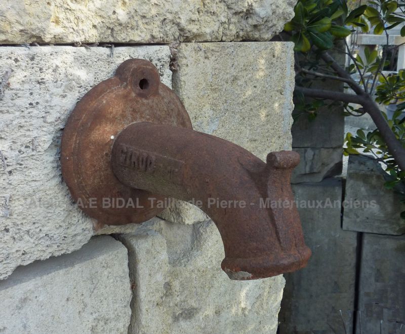 Old water outlet in cast iron on our antique wall fountain in stone.
