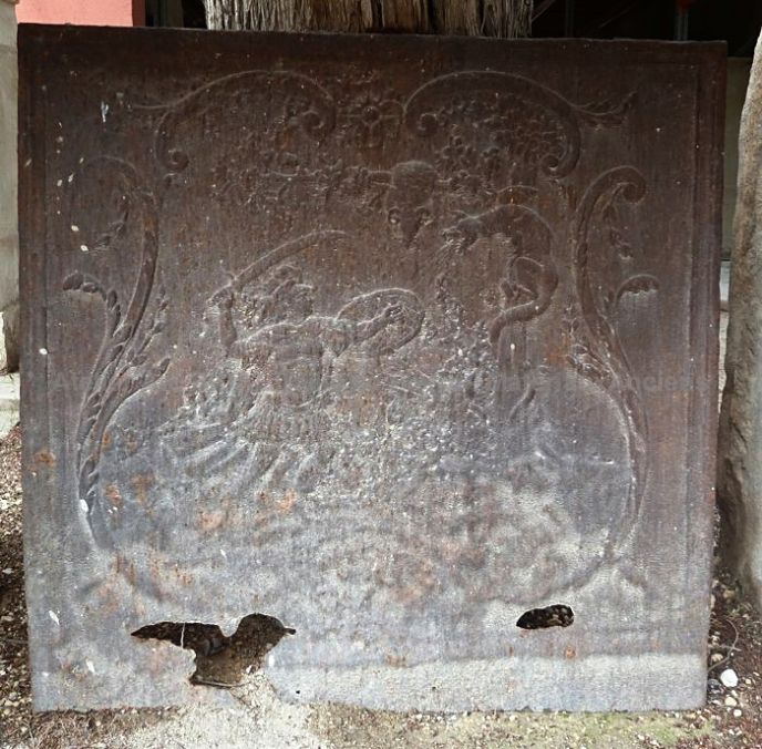 Plaque de cheminée en fonte ancienne représentant une scène d'affrontement dans la mythologie.