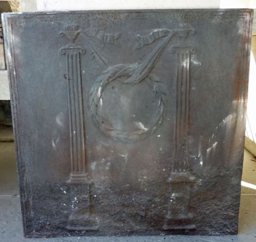 Une plaque de cheminée en fonte de type 19ème siècle décorée de symboles romains - accessoires cheminée en fonte ancienne.