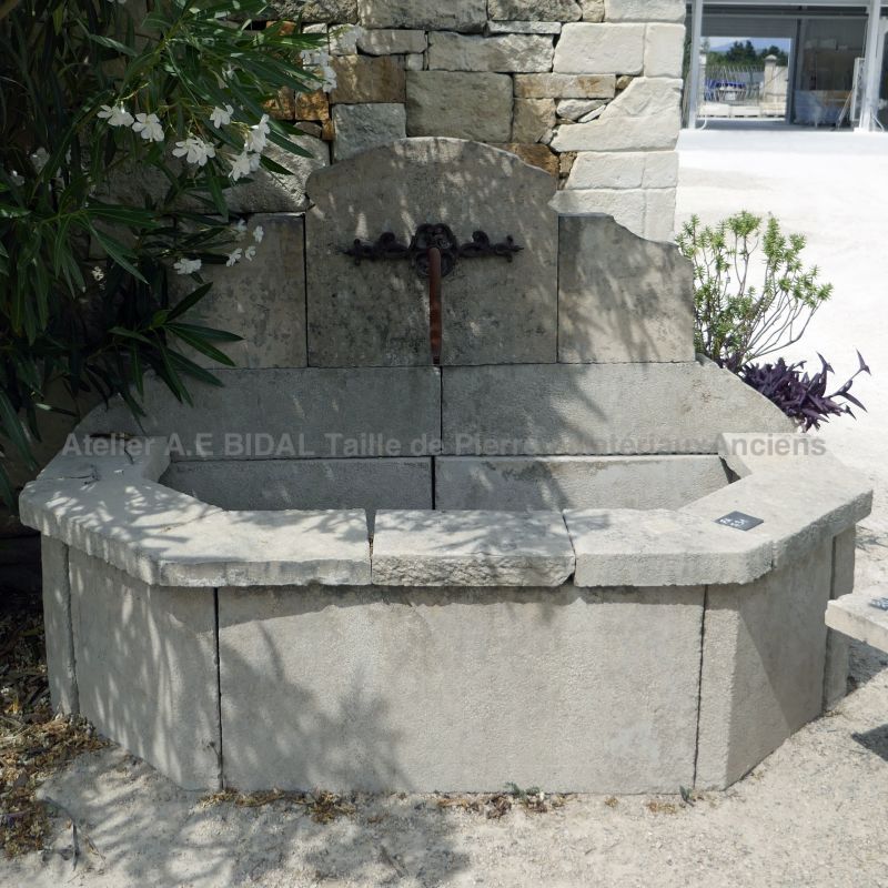 Petite fontaine - une fontaine murale de pierre et de fer forgé.