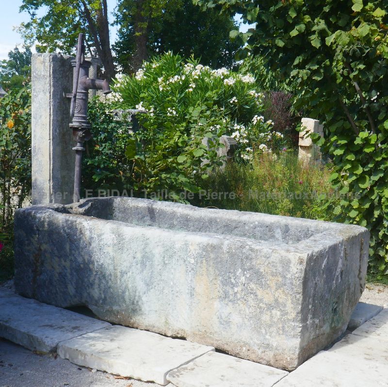 Garden fountain in authentic reclaimed materials : fountain with monolithic trough and cast-iron manual pump
