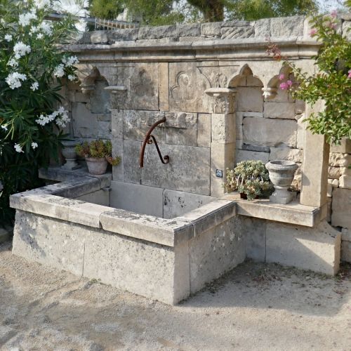 Wall fountain with a gothic stylem made of authentic traditional materials - stone fountain with large pediment.