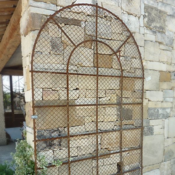 Grille ancienne : une grille en fer forgé qui est grillagée pour plantes grimpantes par exemple.
