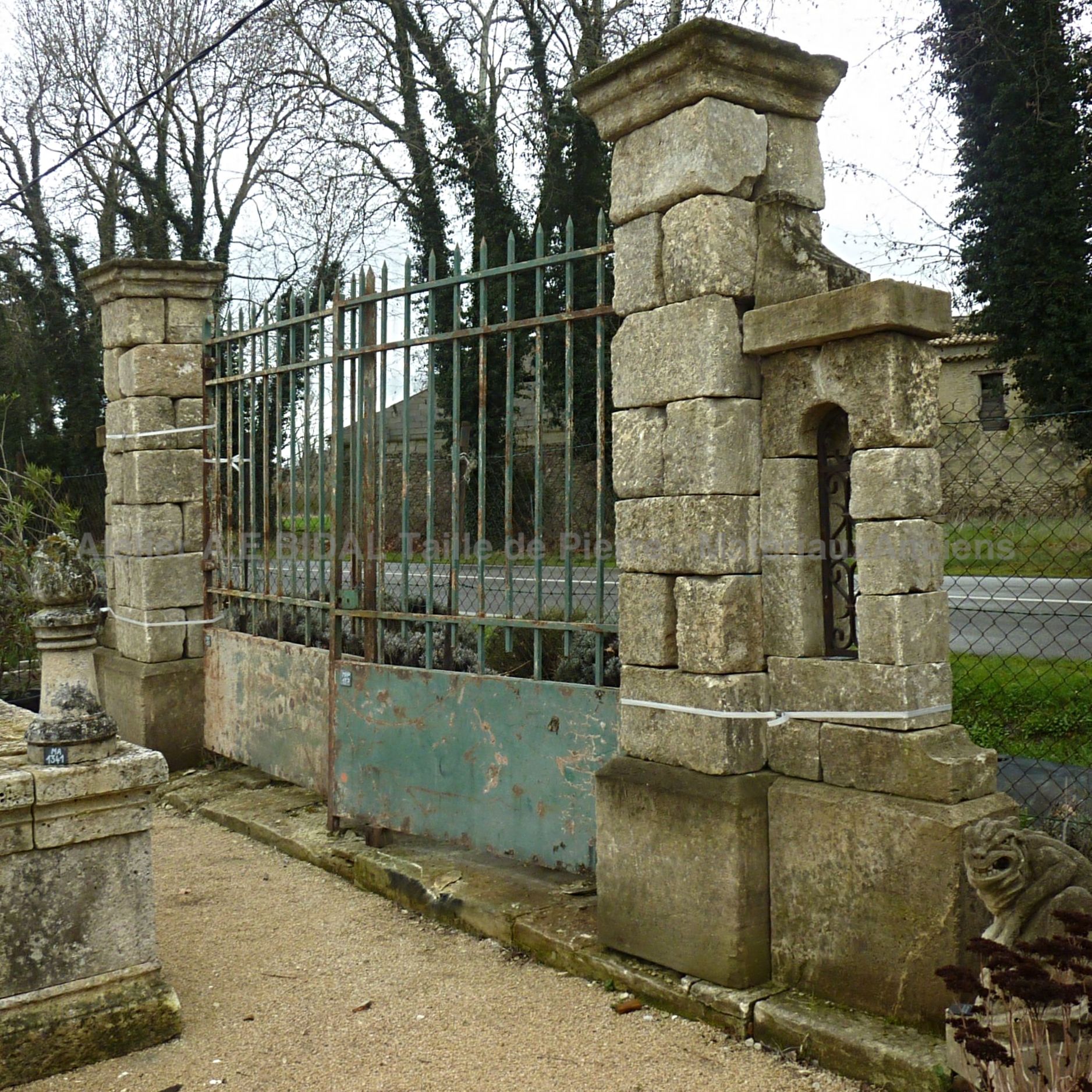 Beau portail ancien en fer forgé - Large portail ancien mis en valeur de part et d'autre par un beau pilier ancien.